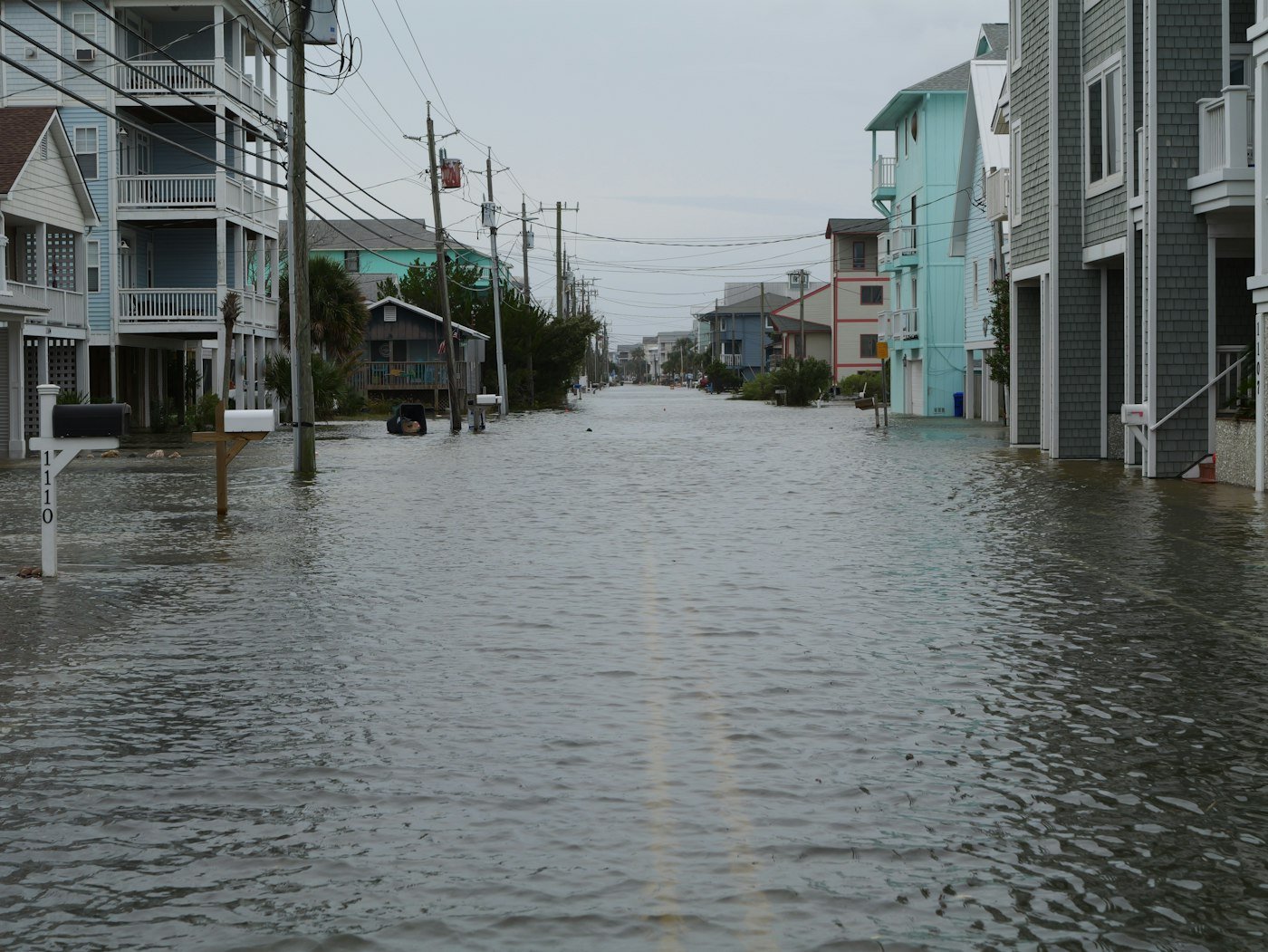 Coastal residential street submerged by tidal storm surge between homes
